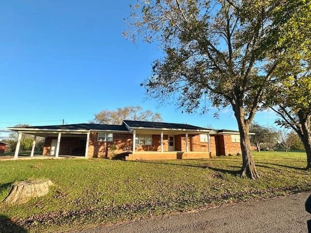 ranch-style house featuring a carport and a front lawn