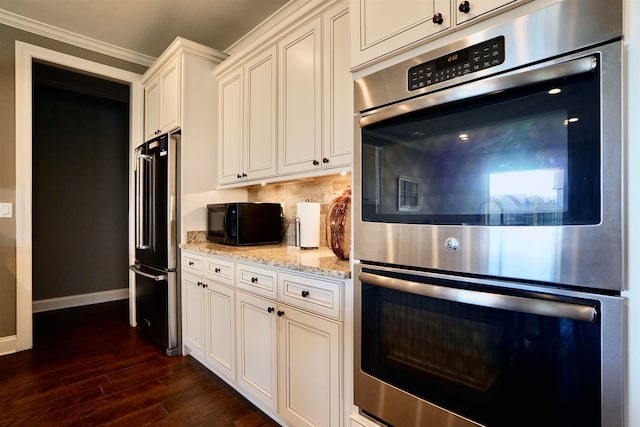 kitchen with dark wood-type flooring, high quality fridge, double oven, light stone countertops, and decorative backsplash