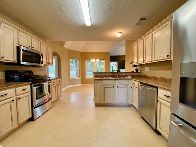 kitchen with sink, hanging light fixtures, stainless steel appliances, kitchen peninsula, and a textured ceiling