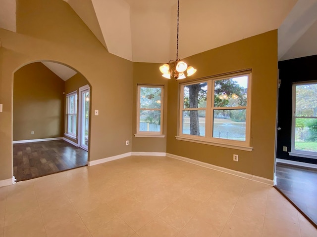 unfurnished room featuring an inviting chandelier, vaulted ceiling, a healthy amount of sunlight, and light hardwood / wood-style floors