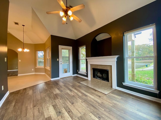 unfurnished living room featuring a tile fireplace, hardwood / wood-style floors, ceiling fan with notable chandelier, and high vaulted ceiling