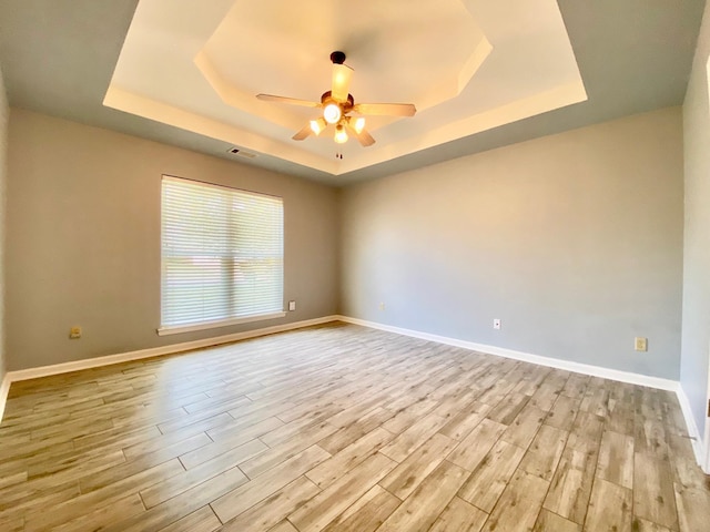 unfurnished room featuring a tray ceiling, light hardwood / wood-style flooring, and ceiling fan