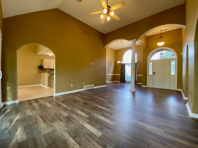 entryway featuring ornate columns, ceiling fan with notable chandelier, high vaulted ceiling, and dark hardwood / wood-style floors