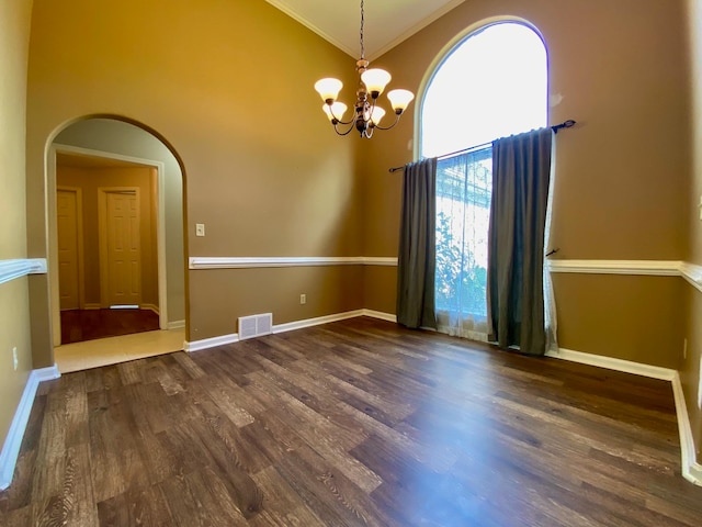 spare room featuring dark hardwood / wood-style floors, high vaulted ceiling, and an inviting chandelier