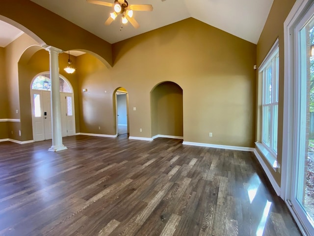 unfurnished living room featuring dark hardwood / wood-style flooring, ornate columns, plenty of natural light, and ceiling fan