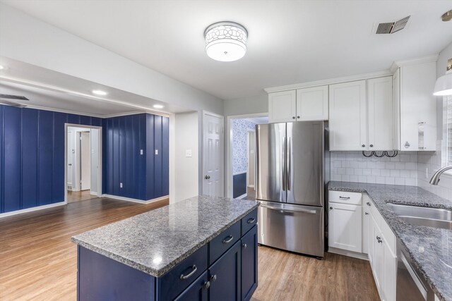 kitchen featuring sink, a kitchen island, appliances with stainless steel finishes, light hardwood / wood-style floors, and white cabinetry