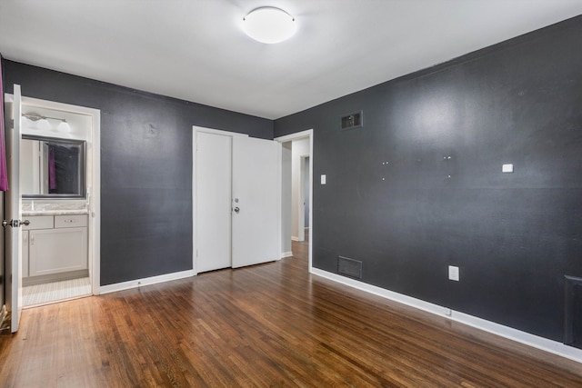 unfurnished bedroom featuring hardwood / wood-style flooring and ensuite bathroom