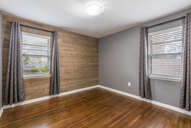 spare room with dark hardwood / wood-style floors and wood walls