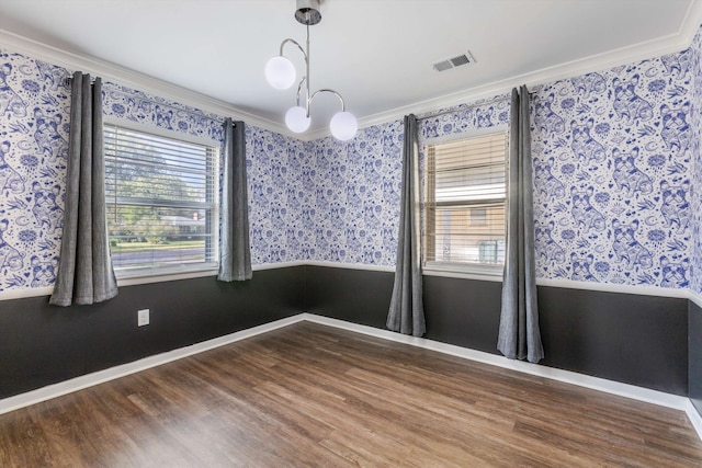 spare room featuring ornamental molding, a healthy amount of sunlight, and wood-type flooring