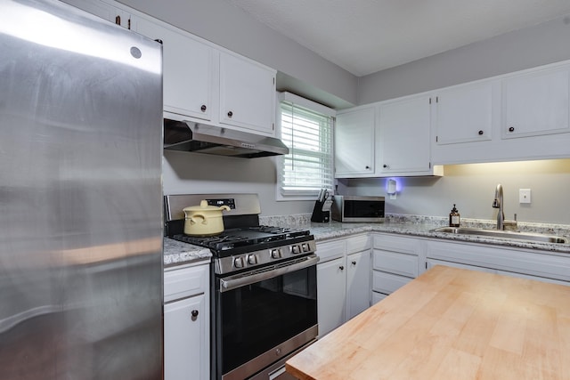 kitchen featuring white cabinetry, sink, light stone countertops, and appliances with stainless steel finishes