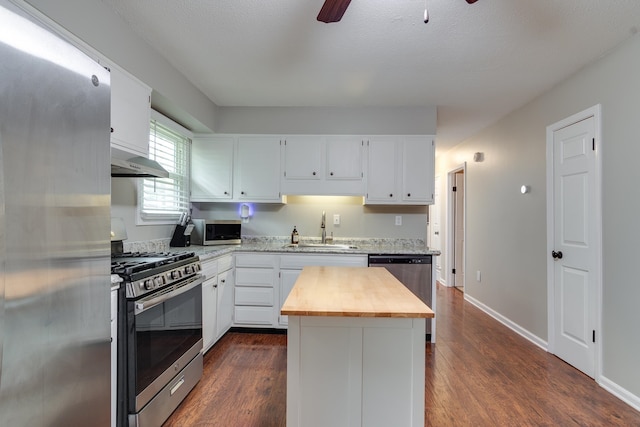 kitchen with stainless steel appliances, a kitchen island, dark wood-type flooring, and sink