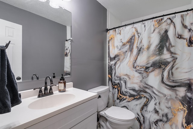 bathroom with vanity, toilet, and a textured ceiling