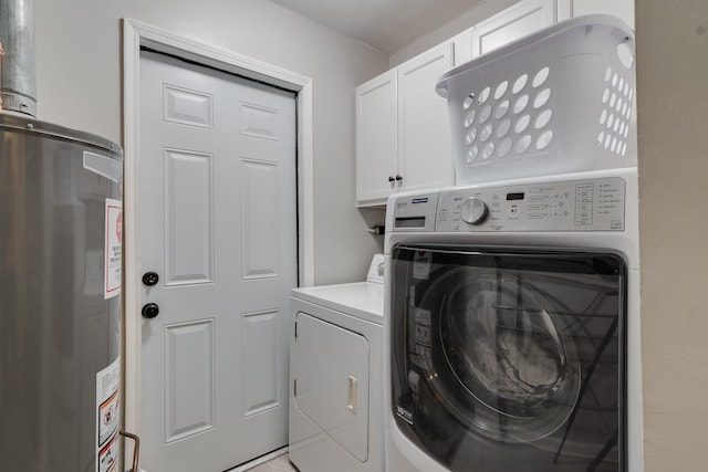 clothes washing area featuring cabinets, washing machine and dryer, and water heater