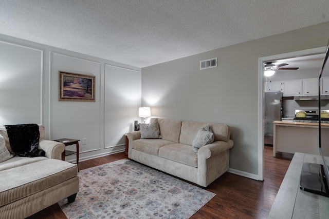 living room featuring a textured ceiling, dark hardwood / wood-style floors, and ceiling fan