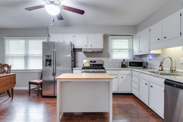 kitchen with stainless steel appliances, dark wood-type flooring, sink, white cabinets, and a kitchen island