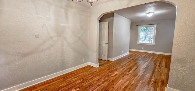 unfurnished room featuring a chandelier and wood-type flooring