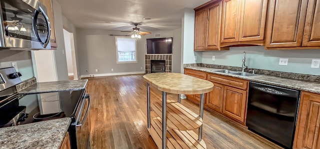 kitchen featuring dark stone counters, sink, ceiling fan, appliances with stainless steel finishes, and dark hardwood / wood-style flooring