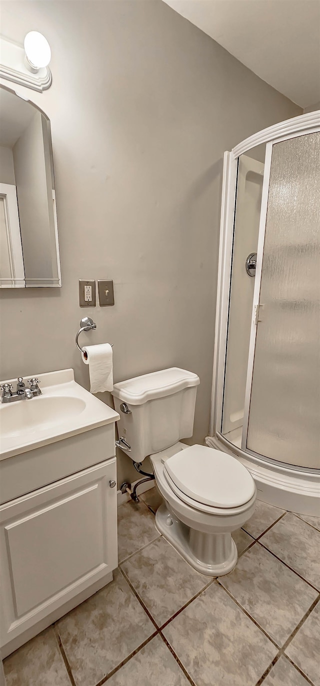 bathroom with tile patterned floors, vanity, toilet, and walk in shower