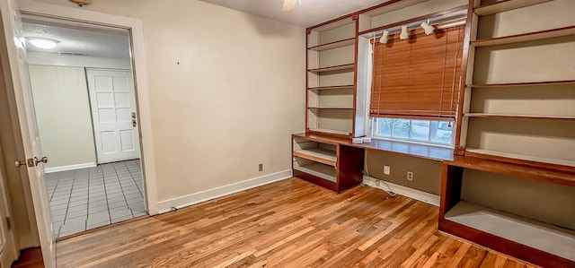 office space featuring built in desk, wood-type flooring, and a textured ceiling