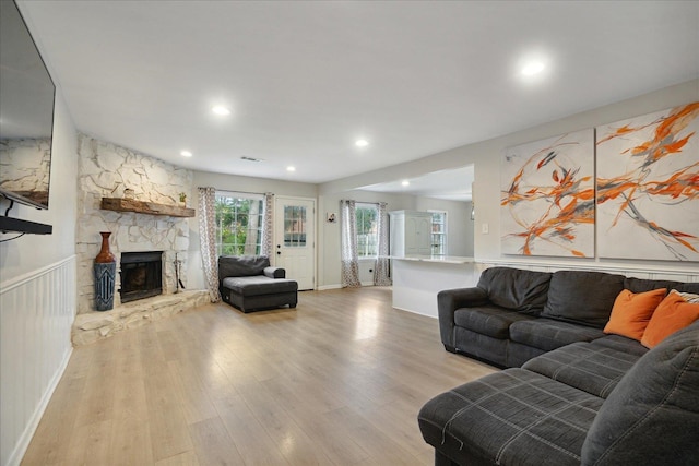 living room featuring a stone fireplace and light hardwood / wood-style flooring