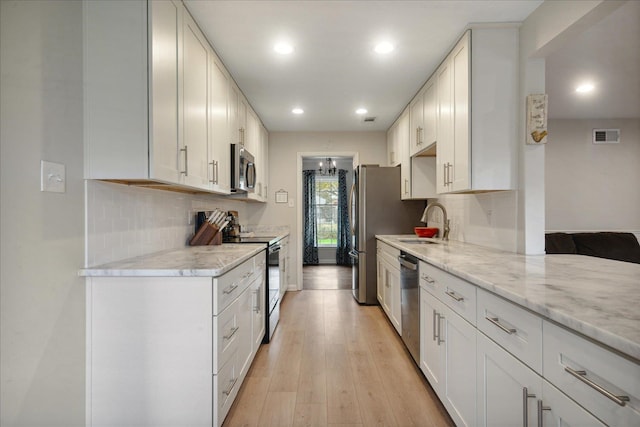 kitchen with stainless steel appliances, white cabinetry, light hardwood / wood-style floors, and sink