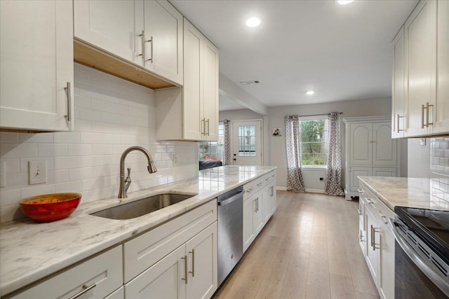 kitchen featuring sink, stainless steel appliances, light stone counters, light hardwood / wood-style floors, and white cabinets