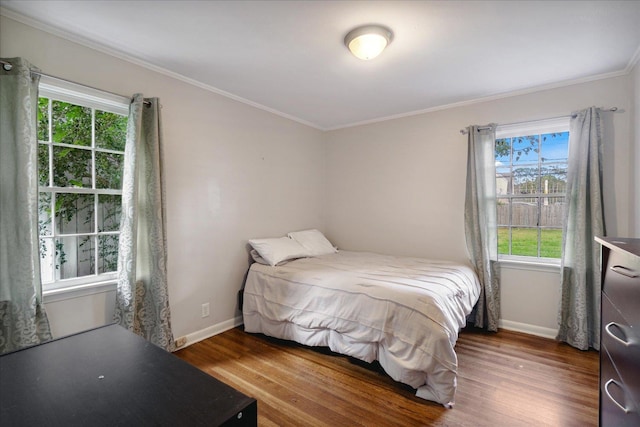 bedroom featuring dark hardwood / wood-style flooring, multiple windows, and ornamental molding