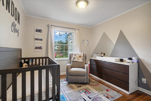 bedroom featuring dark hardwood / wood-style flooring, a nursery area, and ornamental molding