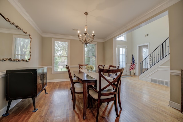 dining space with light hardwood / wood-style floors, plenty of natural light, crown molding, and a notable chandelier