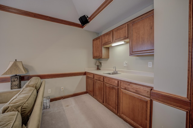 kitchen featuring crown molding, sink, light colored carpet, and lofted ceiling