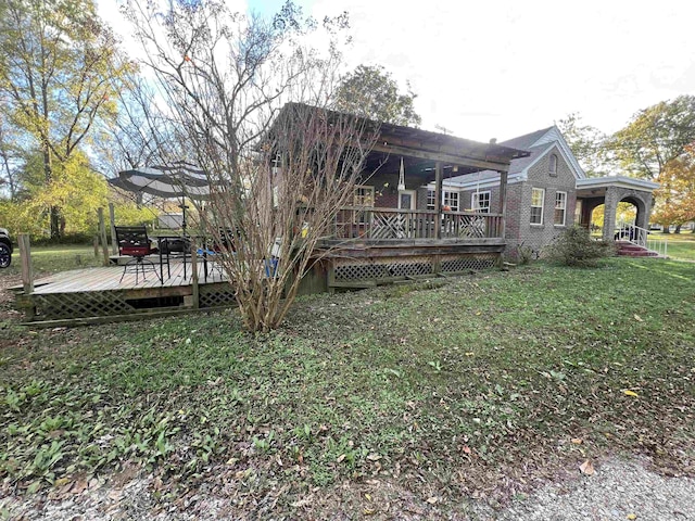 rear view of property featuring a lawn and a wooden deck