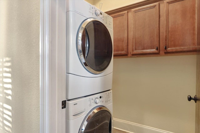 washroom featuring cabinets and stacked washer and clothes dryer