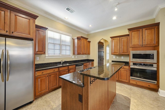 kitchen with sink, a kitchen island, light tile patterned flooring, and appliances with stainless steel finishes