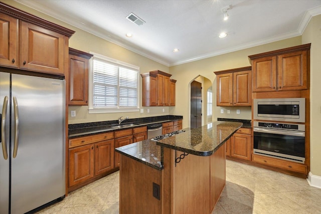 258 S Mclean Blvd, Memphis, TN 38104 - kitchen featuring stainless steel appliances, a sink, a center island, arched walkways, and light tile patterned floors