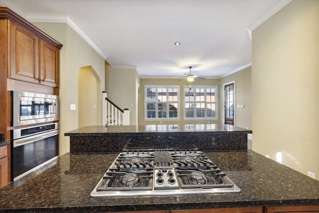 258 S Mclean Blvd, Memphis, TN 38104 - kitchen featuring appliances with stainless steel finishes, ornamental molding, arched walkways, brown cabinets, and a ceiling fan