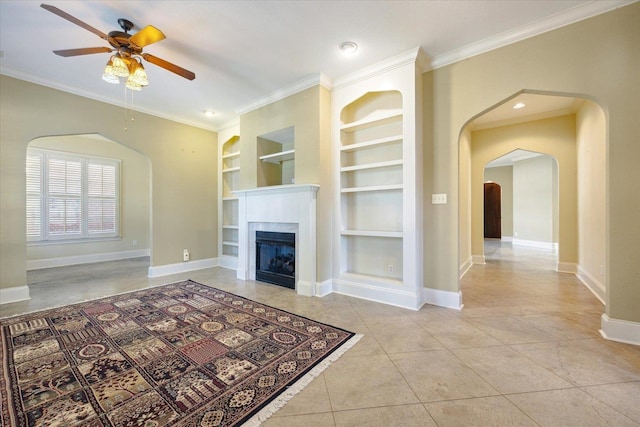 unfurnished living room featuring ceiling fan, built in features, ornamental molding, and light tile patterned floors