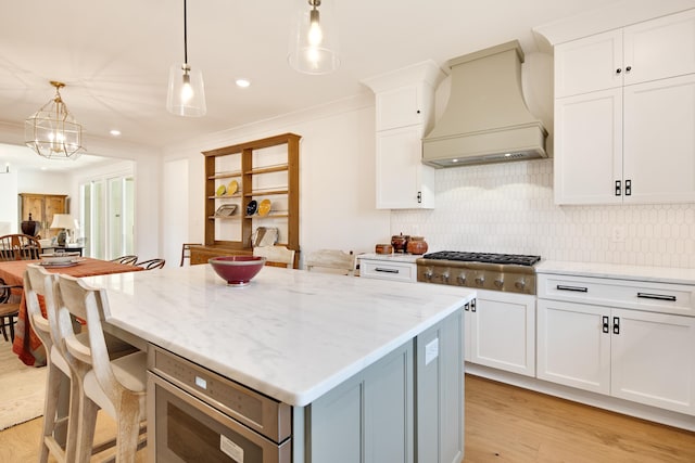 kitchen with premium range hood, light hardwood / wood-style flooring, and white cabinets