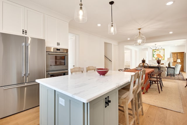 kitchen with white cabinets, a center island, light wood-type flooring, and stainless steel appliances