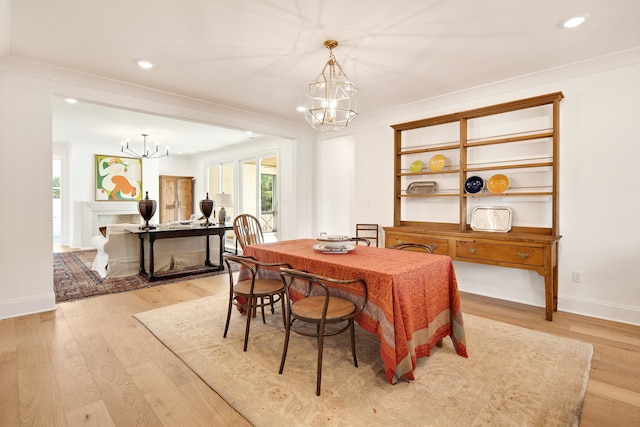 dining area with a notable chandelier, light wood-type flooring, and crown molding