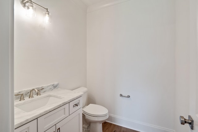 bathroom featuring ornamental molding, vanity, wood-type flooring, and toilet