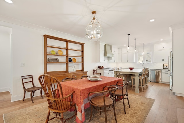 dining room with sink, a notable chandelier, and light wood-type flooring