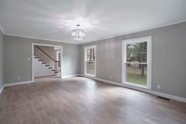 empty room featuring ornamental molding, a notable chandelier, and hardwood / wood-style flooring