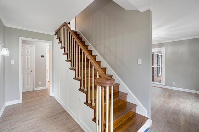 staircase with wood-type flooring and ornamental molding