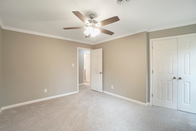 unfurnished bedroom with a closet, crown molding, ceiling fan, and light colored carpet