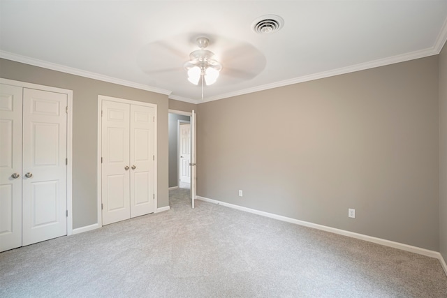 unfurnished bedroom featuring ceiling fan, crown molding, light carpet, and two closets