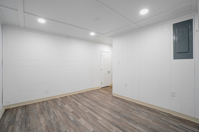 spare room featuring wood walls, dark wood-type flooring, and electric panel