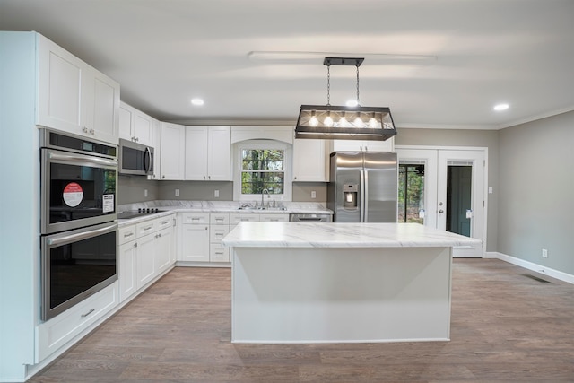 kitchen with a center island, hanging light fixtures, stainless steel appliances, light hardwood / wood-style floors, and white cabinets