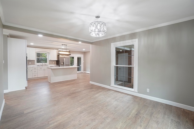 unfurnished living room with a chandelier, crown molding, and light hardwood / wood-style flooring