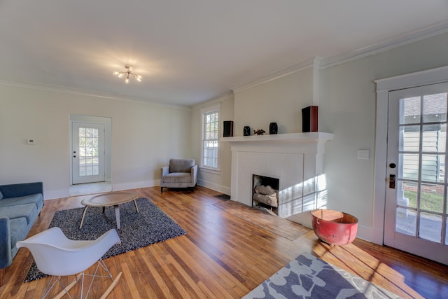 living room with a brick fireplace, hardwood / wood-style floors, and ornamental molding