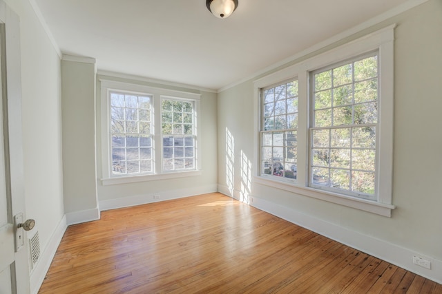 unfurnished room with light hardwood / wood-style floors, a wealth of natural light, and crown molding